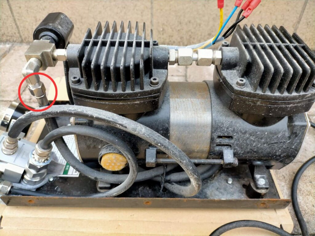 アネスト岩田 IS-925 エア漏れ原因箇所を示した側面図。赤丸で示したネジの緩みがエア漏れの原因。11mmスパナで増し締めして修理。カバー固定ネジ6本取り外し後の本体側面