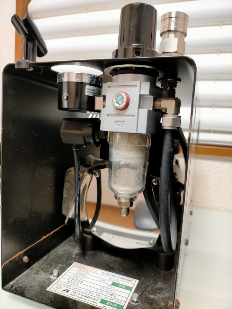アネスト岩田 IS-925 ミニコンプレッサーのメンテナンス前の状態。電源を入れるとエア漏れ音が発生し、エアレギュレーターのガラスケース内に白い粉が大量に堆積した状態。エアブラシ用オイルフリーコンプレッサーの清掃・修理前