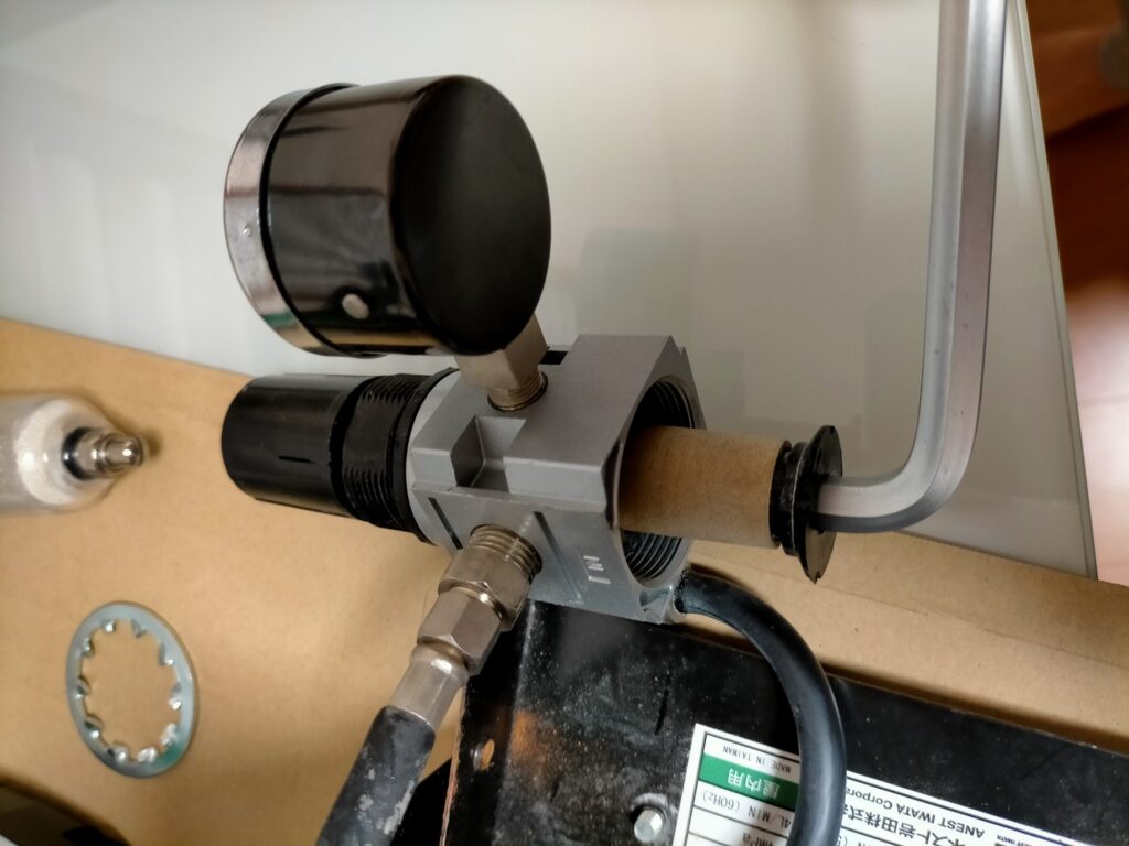 アネスト岩田 IS-925 エアレギュレーターのモイスチャーフィルターを8mm六角レンチで取り外している状態。ガラスケースはねじ込み式で固く、外す際に割れ注意。白い粉が詰まったレギュレーター分解清掃手順