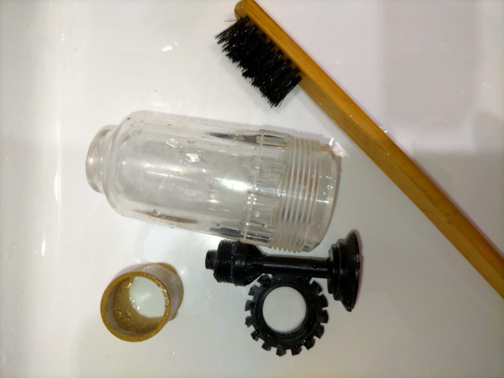 アネスト岩田 IS-925 エアレギュレーター分解部品の水洗い清掃中。モイスチャーフィルター・ガラスケース・各パーツを水洗い。真鍮ジェットの細管はエアガンで白い粉を吹き飛ばして清掃