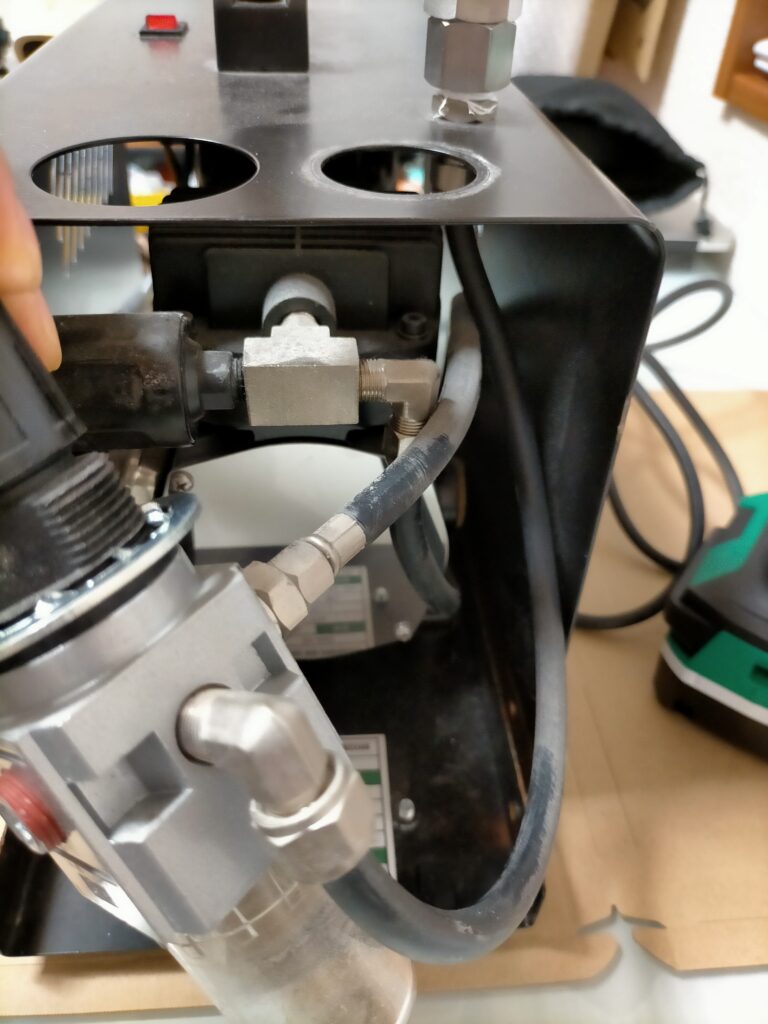 アネスト岩田 IS-925 上カバー取り外し作業中。カバーに固定されているレギュレーターを取り外している状態。エアホース差込口・エアブラシホルダーも順に外す手順