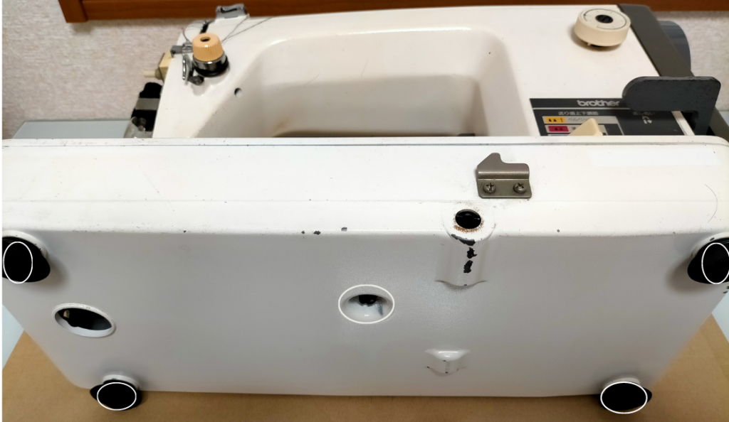 brother TA3-B627 職業用ミシンを寝かせて底カバーを外す際の止めネジ5本(白丸)の位置を示した図解。底カバー取り外しで釜(ボビン釜)へのアクセスが可能になる。釜調整に必要な底カバー取り外し手順