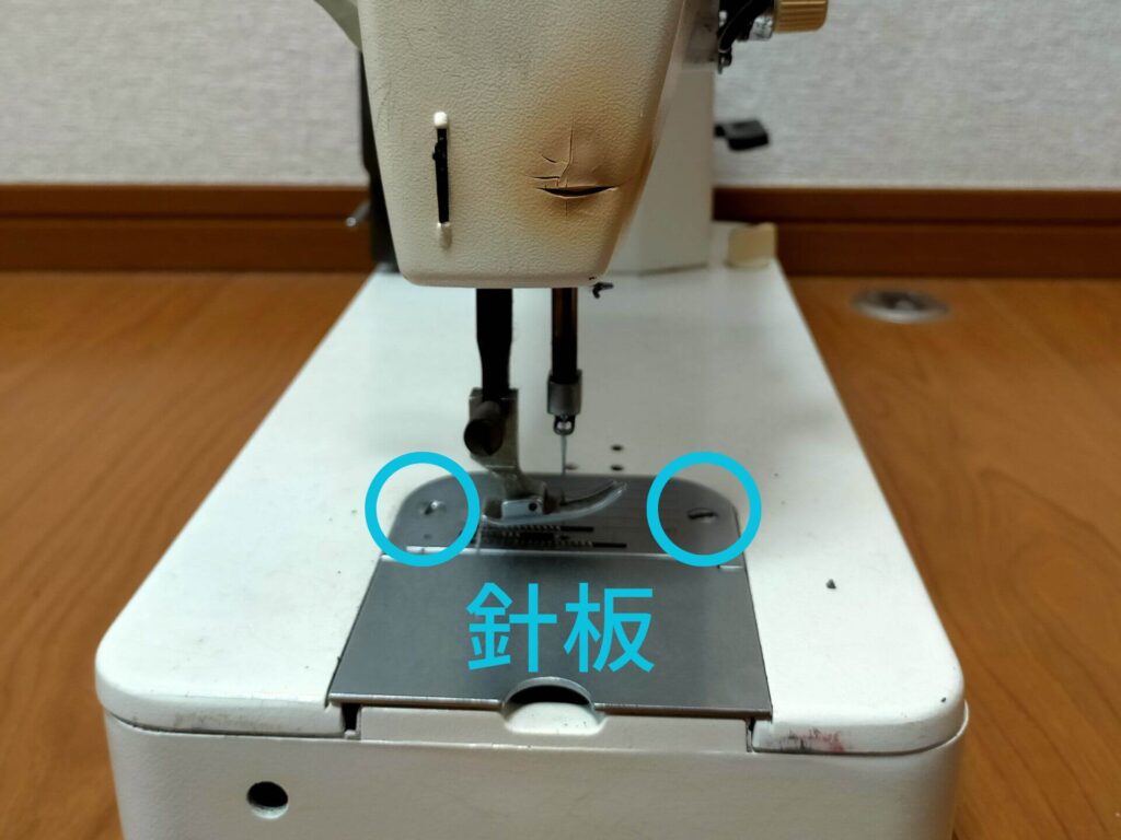 brother TA3-B627 職業用ミシンの釜調整前に外す針板押さえの止めネジ2本(白丸)の位置を示した図解。釜調整作業開始前に針板押さえを先に外しておくと後の作業が楽になる。釜調整の準備手順