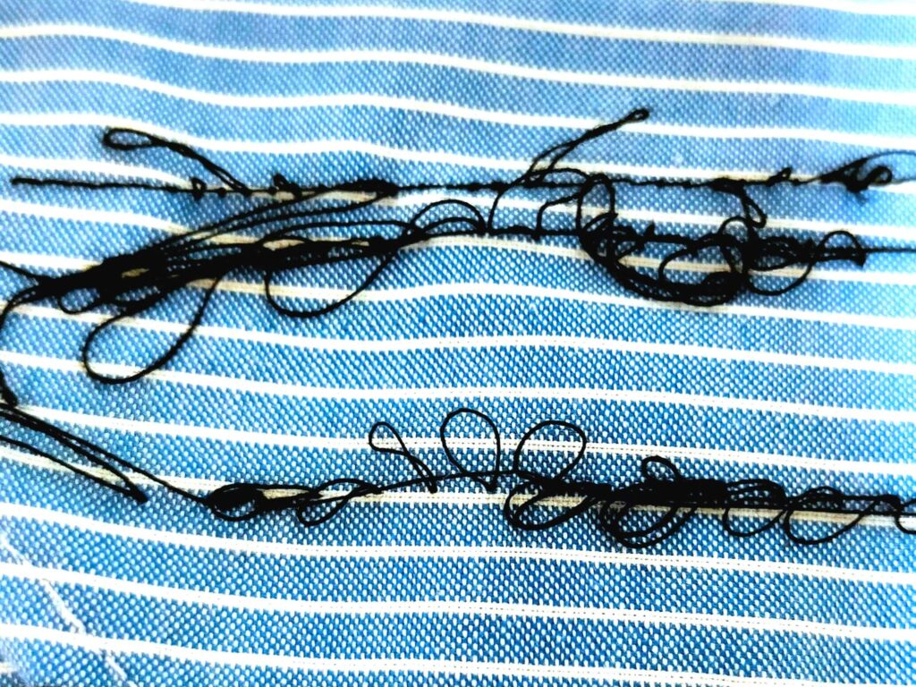 brother TA3-B627（Nouvelle Couture SPECIAL Ⅱ）職業用ミシンで下糸がぐちゃぐちゃになった縫い目の状態。糸調子ツマミの締め込みが甘いことが原因で、下糸がたるんで布の裏面に大量の糸がループ状に出ている。ボビンケース調整ではなく上糸の糸調子を強く締めることで改善する