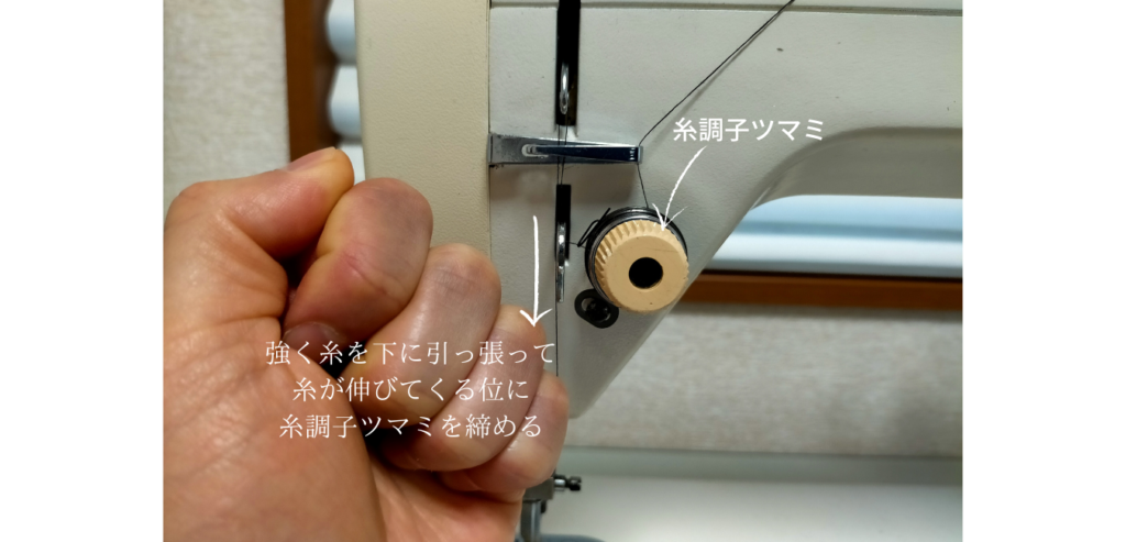 brother TA3-B627 職業用ミシンの糸調子ツマミを手で強く引いてやっと糸が伸びてくる程度まで強く締め込む調整方法。目盛りなしのツマミの正しい締め込み量を示した写真。締めすぎると針から糸が抜けたり布が突っ張るため適度な調整が必要
