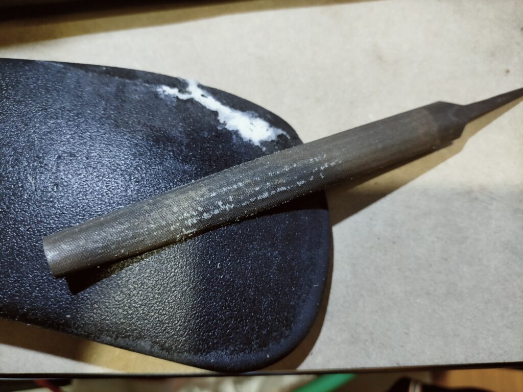 オカムラ コンテッサ肘パッド修理STEP2・シリコンオフで脱脂後にセメダインEP001Nをパテ代わりに欠け・崩れ部分に盛り付け乾燥後にヤスリで削り平滑に整形している作業。接着剤の密着性を高めるための下地処理