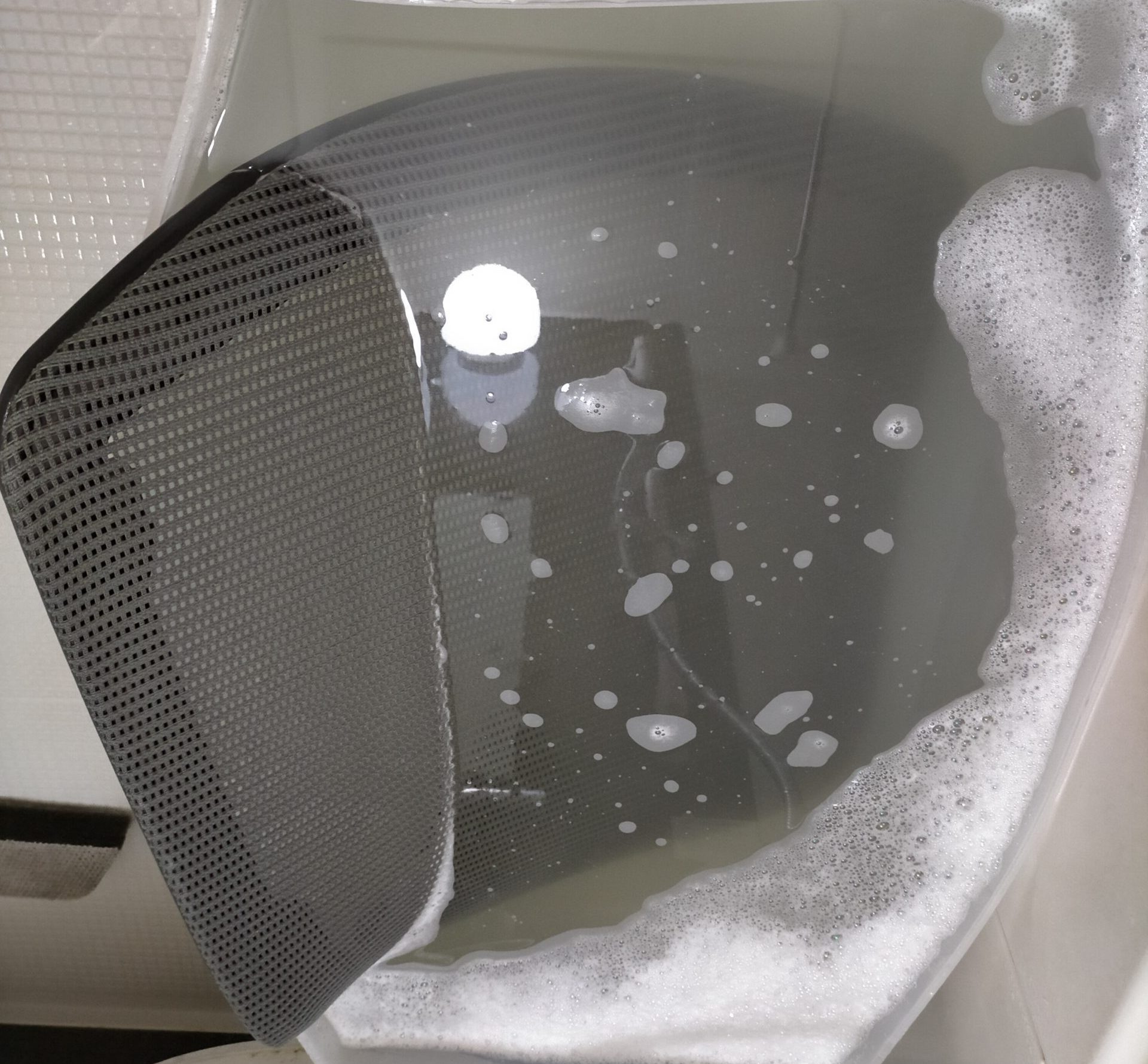 オカムラ コンテッサの背メッシュフレームを衣装ケースに洗濯洗剤＋セスキ炭酸ソーダ溶液で浸け置き洗いしている様子。中古で購入した生臭い背メッシュの臭い除去・丸洗い洗濯方法の解説記事アイキャッチ