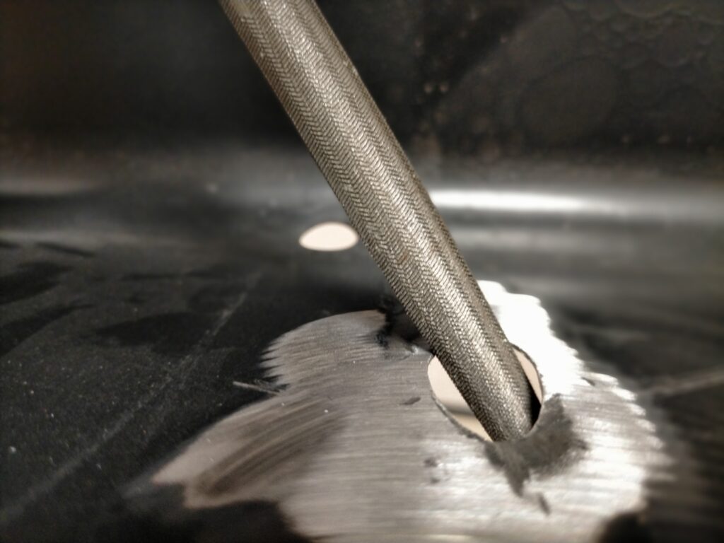 サンワ 100-KB004 キーボードケーブルを通す穴（タガネで偶然開いた穴）のバリをグラインダー・板金作業で取り除いた完了状態。キーボードスライダーのケーブル配線穴として活用するDIYアイデア。塗装前の最終仕上げ状態