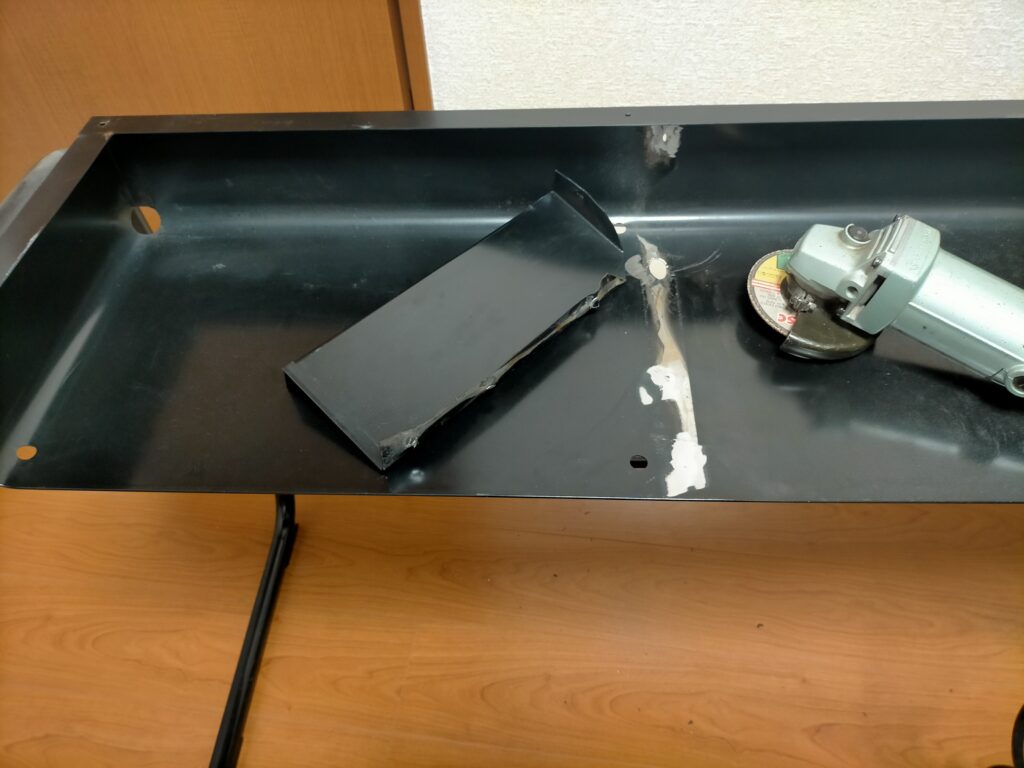 サンワ 100-KB004 キーボードスライダー取り付け作業Step2完了。タガネでスポット溶接を切り離した際に勢い余って下の鉄板に穴が開いた状態。この穴がキーボードのケーブルを通すのに最適なサイズで、穴あけ手間が省けた「怪我の功名」。間仕切り撤去後・グラインダーでバリ取り前