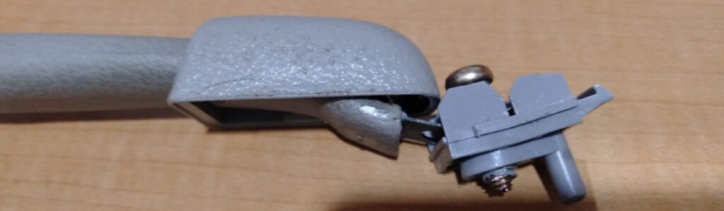 いすゞコモ（E25キャラバン）助手席上のアシストグリップ本体を裏カバー取り外し後にクリップから外している作業写真。ルームランプ2箇所はプラスネジで取り外し、グリップはクリップ止めのため破損に注意が必要な工程