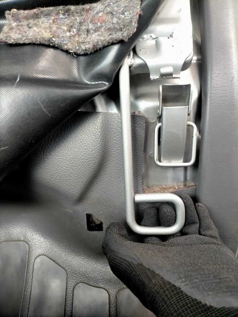 E25キャラバン／コモのエンジンアクセス手順ステップ3・助手席の座席全体を取っ手を持って跳ね上げている状態。ロック解除後・背もたれ前倒し後にシートアセンブリを上方向に持ち上げることでKA24DEエンジンルームが完全露出する。座席は重いため落下に注意