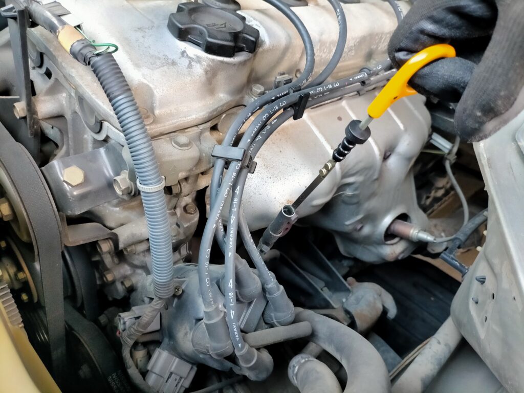 エンジンオイルレベルゲージの口から、レベルゲージを抜いている様子