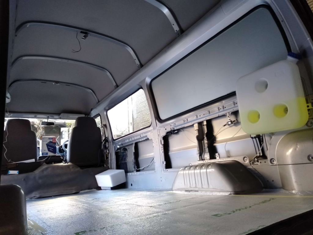 いすゞコモ（E25キャラバン）の床面に純正タール制振材の上からGSメタルシートMS-2（厚さ5mm）を両面テープで貼り付けたフロア施工の状態。軽く脱脂した純正タール材の上に直貼りするDIY手順STEP2。この上に15mm MDFボードを敷くと気泡が潰れ断熱性能低下の可能性あり、スタイロフォーム併用を推奨