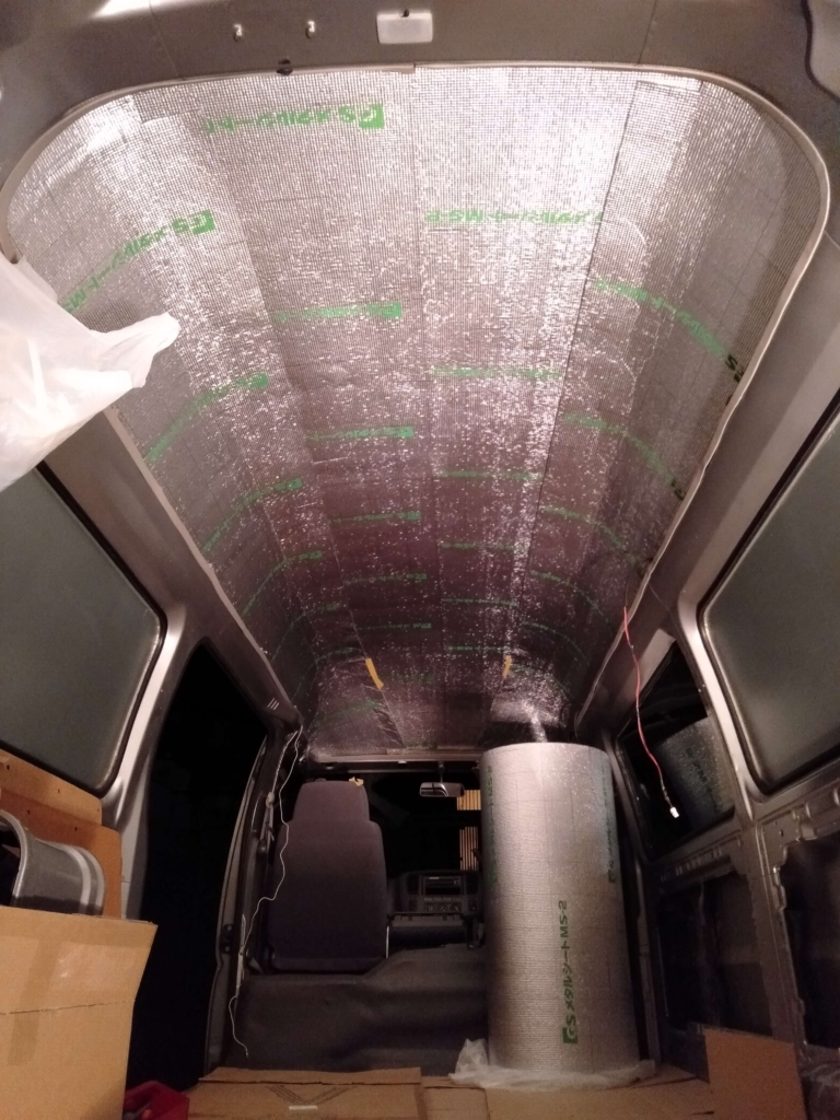 車中泊カスタムとして、キャラバンの天井鉄板にメタルシート（断熱材）を隙間なく貼り付けている施工風景