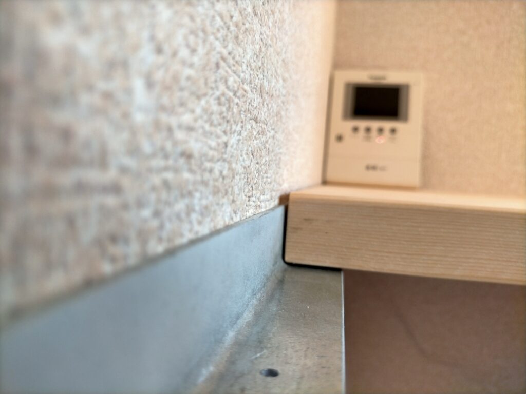 空中デスクDIY・赤松集成材の天板（2560mm）をアングルに仮置きして高さ・水平・バランスを確認している工程。アングルの角（アール部分）に天板裏が当たって少し浮く場合は裏面を面取りして逃がす必要がある。棚アングルと机アングルを合わせたL字書斎全体のレイアウト確認