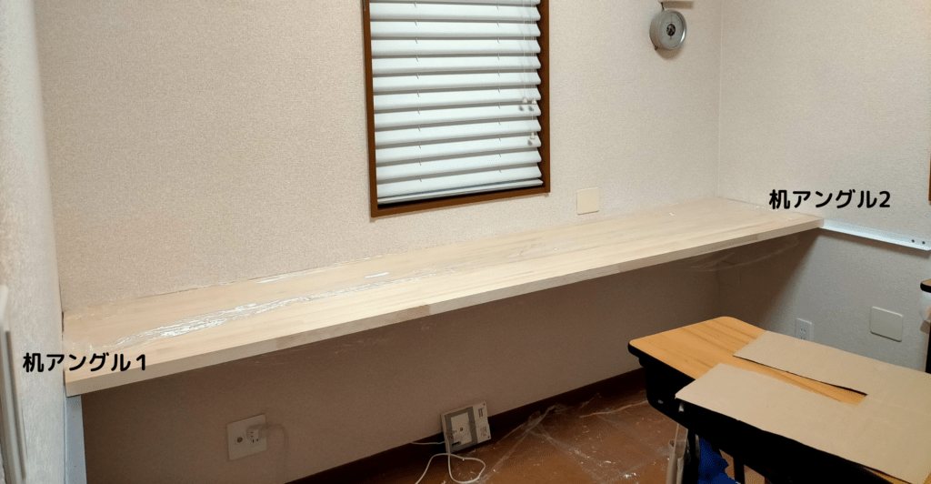 空中デスクDIY・メインデスク用に壁へ固定した白塗装アングル2本の完成状態。4.8×75mmコーススレッドで柱・間柱に複数本固定されたアングルが水平に並んだ状態。この上に赤松集成材の天板（2560mm）を乗せて皿ビス3×25mmで下から固定する。脚のない「空中」を支える構造