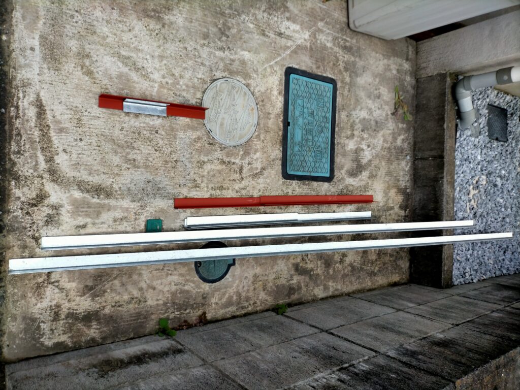 フローティングシェルフ＆空中デスクDIY用にチップソー切断機でカットしたアングル6本（上2本は端材）。棚用4本＋机用2本。メッキアングルとカラーアングルの混在。この後5mm穴（壁固定用）と3mm穴（棚板固定用）をドリルで加工する