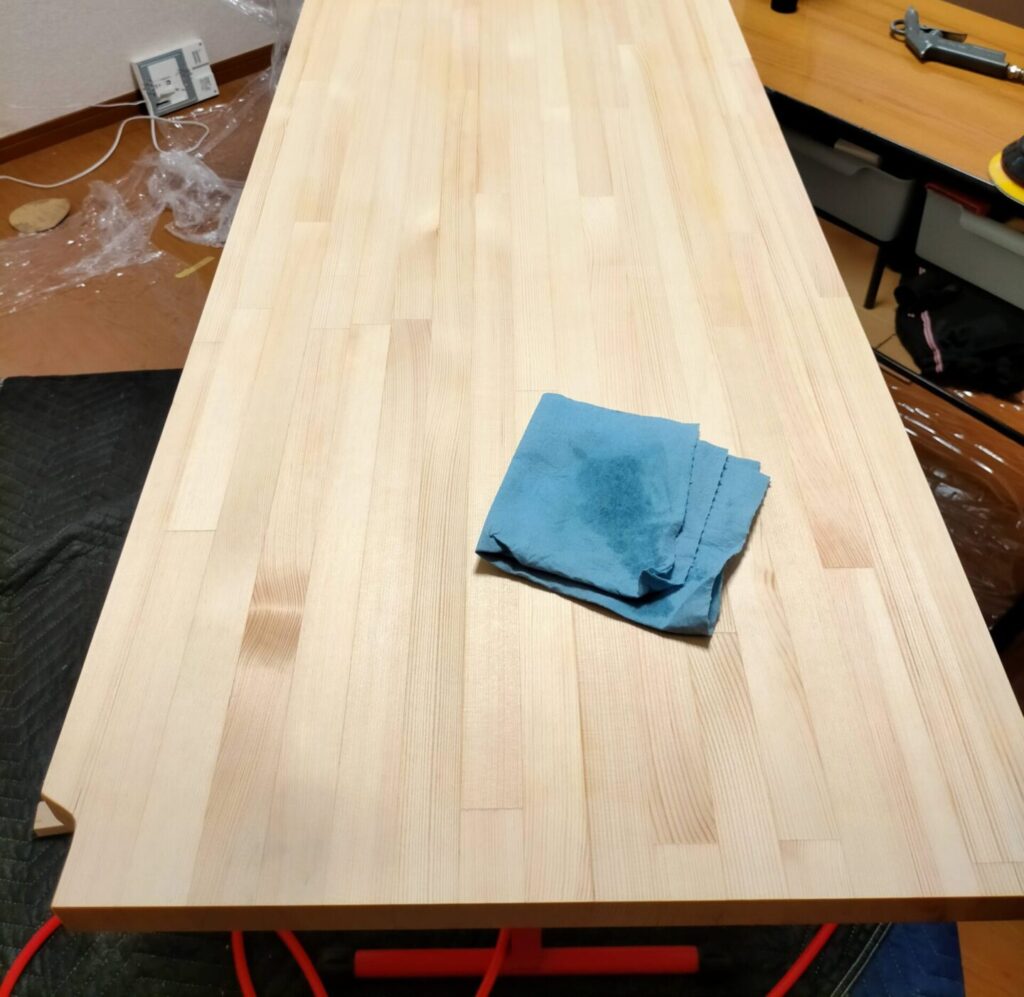 フローティングシェルフDIY・パイン集成材の棚板に蜜蝋ワックス(BEEWAX)またはワトコオイル・ブライワックスを布で塗布している仕上げ工程。オイル塗布でパイン材の木目が引き立ち、撥水・傷つき防止効果も付与。スコットショップタオルで塗布・拭き上げ