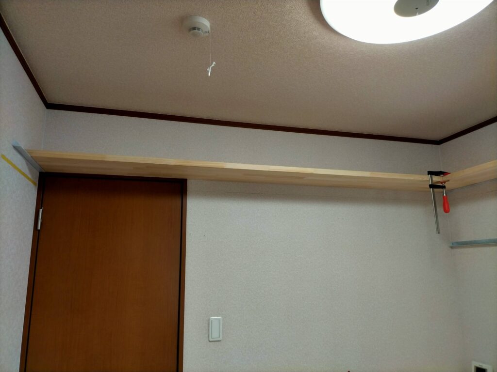 フローティングシェルフDIY・上段棚板をアングル2本に乗せて壁設置した状態。雇いざね接合済みのパイン集成材(4200×600×30mm)がアングル上に固定され、壁から「浮いている」ように見えるフローティングシェルフ上段の設置完了写真。ザグリ穴処理でビス頭が見えない