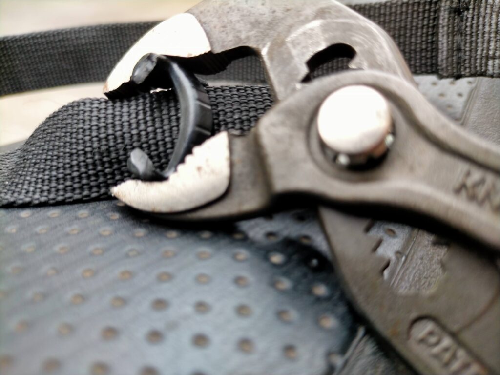 タンクバッグバックル交換STEP3・割れたNIFCO TSR-20オス側の残骸をKNIPEXコブラプライヤーで完全に割り取って除去している工程。破損した古いバックルをベルトから取り外す最終作業。この後新品のオス側を取り付けてメス側と接続し修理完了