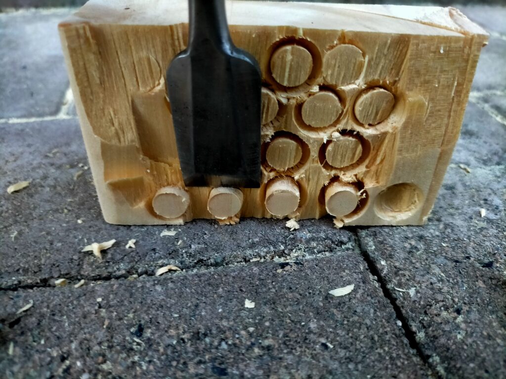 DIYザグリ穴隠し用木ダボの自作工程・のみ(追入のみ)でΦ10木ダボドリルで削り出した木ダボを端材から折り取っている状態。折り取ることでザグリ穴に差し込む木ダボ単体が完成。長さはザグリ穴深さ10mmより少し長めに折り取ることで後から板面と面一に削りやすい