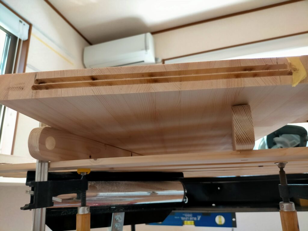 DIY雇いざね加工ステップ3・トリマーガイドを6mmずらした後のサブ机（幅380mm）への2回目のメスザネ溝加工。1回目の溝と合わせて合計12mm幅の溝が完成。ガイドのずらし量が正確でないと雇いざねがきつすぎ・緩すぎになるため6mmずらしの精度が仕上がり品質を決める