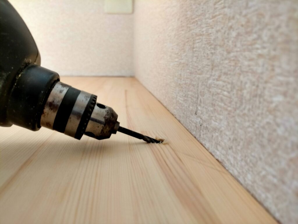 DIYザグリ穴隠しステップ2・ザグリ穴の中心に5mmキリで下穴をあけている工程。下穴を先にあけることで5×80mmコーススレッドが真っ直ぐ入り、板の割れを防止する。ザグリ穴(10mm径)の中心に正確に下穴(5mm径)を合わせることでビスが垂直に入る