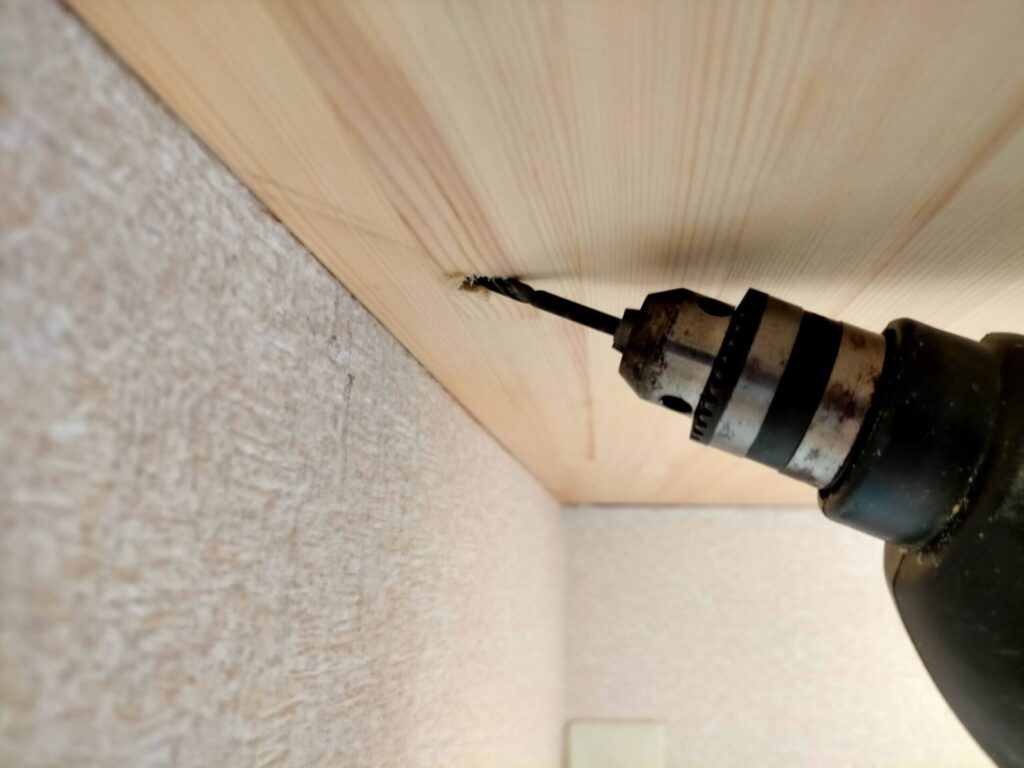 DIYザグリ穴隠しステップ2・ザグリ穴の中心に5mmキリで下穴をあけている工程。下穴を先にあけることで5×80mmコーススレッドが真っ直ぐ入り、板の割れを防止する。ザグリ穴（10mm径）の中心に正確に下穴（5mm径）を合わせることでビスが垂直に入る