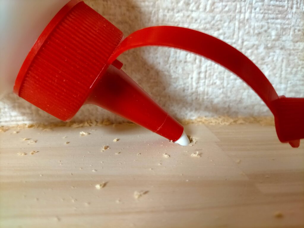 DIYザグリ穴隠しステップ5・Φ10mmのザグリ穴の内側に木工用ボンド(コニシ木工用速乾)を塗っている工程。ボンドは穴の壁面全体に薄く均一に塗ることで木ダボとの接着面積を最大化する。隙間がある場合はボンドで錬った木くず(木粉パテ)で充填する