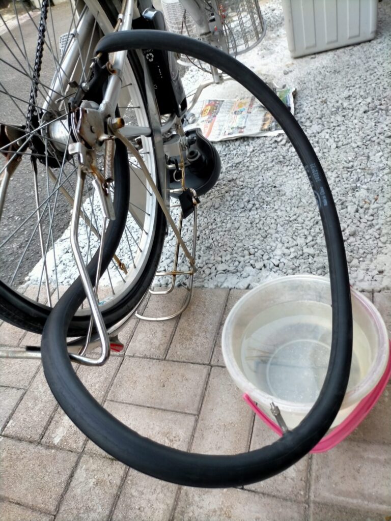自転車パンク修理ステップ3・チューブに空気を入れてパンク箇所を特定する手順。取り出したチューブにプランジャーとトップナットを一時的に戻して空気を充填。この後バケツの水に少しずつ浸して気泡が出る場所＝穴の位置を確認する