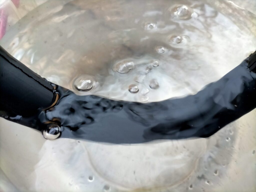 自転車パンク修理ステップ3・水を張ったバケツにチューブを浸して気泡が出るパンク箇所を発見した状態。空気漏れ箇所から泡が連続して出ている。穴は複数ある場合もあるため必ず一周全体を確認すること