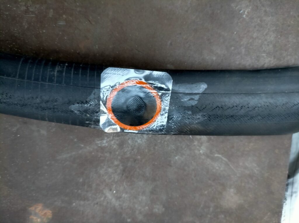 自転車パンク修理ステップ4・ゴムのりが乾燥したチューブにパッチ（補修パッチ）のアルミ箔を剥がして貼り付ける工程。穴が中心に来るよう位置を合わせてから貼り付ける。この後ゴムハンマーで叩いて完全に密着させる