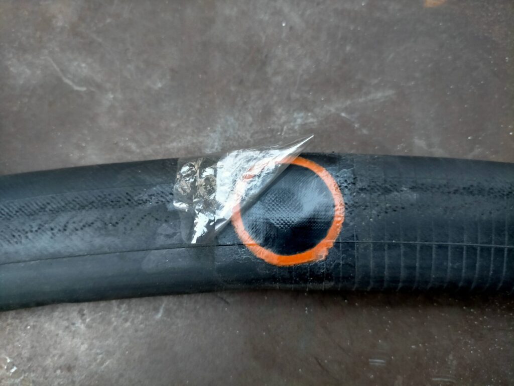 自転車パンク修理ステップ4・ゴムハンマー圧着後にパッチ表面の透明保護フィルムを剥がす最終工程。フィルムを剥がしたら再度水バケツに浸して空気漏れがないか最終確認を行う。完全密着していれば気泡なしで修理完了