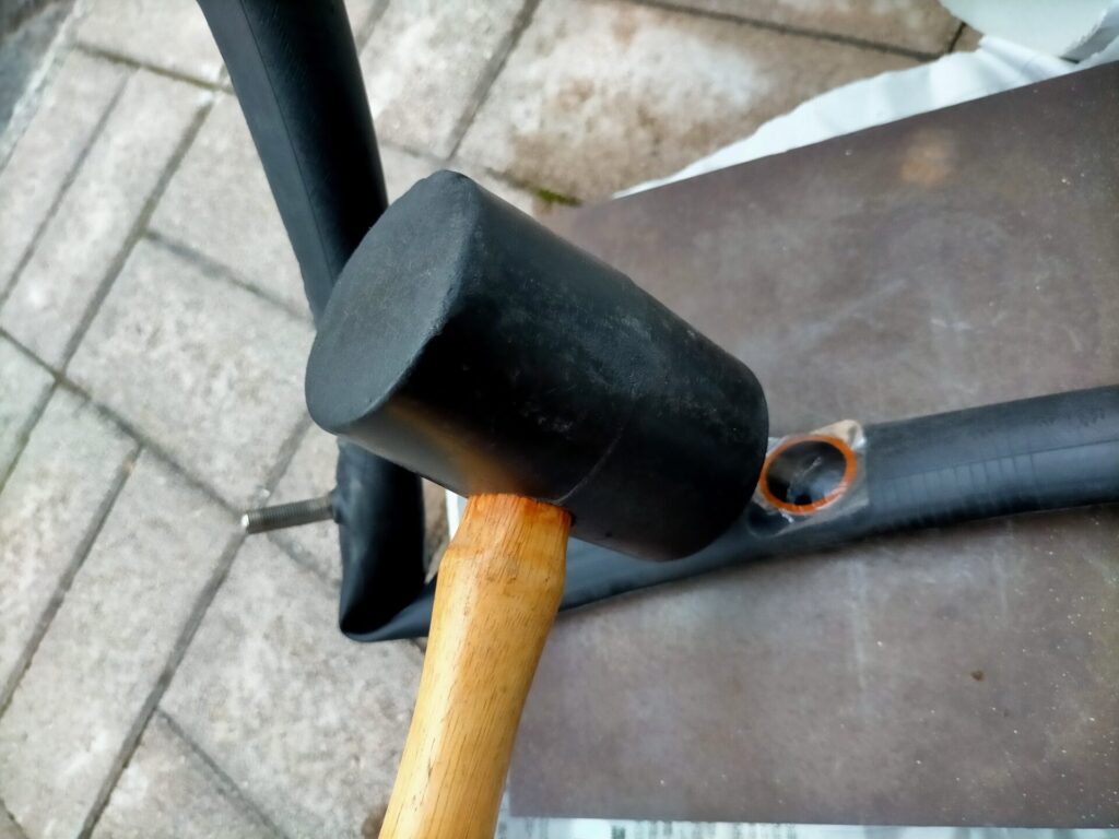 自転車パンク修理ステップ4・パッチ貼り付け後にゴムハンマーでトントンと叩いて圧着する工程。ハンマーで叩くことでパッチとチューブを完全に密着させ剥がれを防ぐ。圧着後にパッチ表面の透明フィルムを剥がして完成