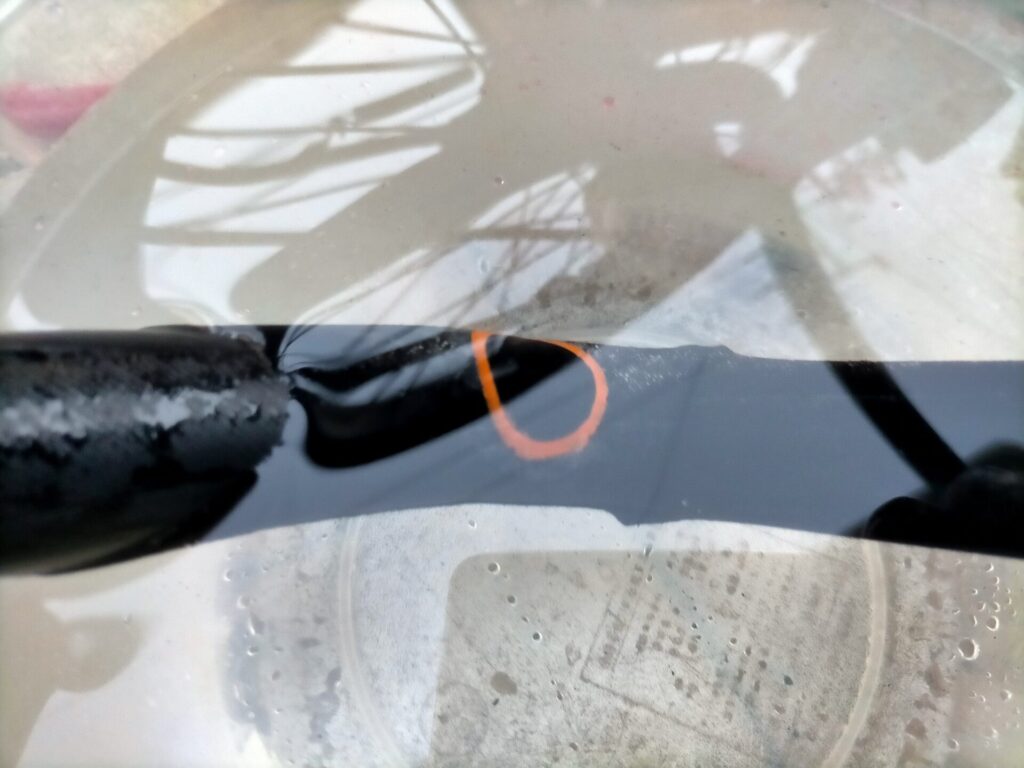 自転車パンク修理ステップ5・パッチ貼り付け後の最終確認。チューブを再度水バケツに浸して気泡が出ないことを確認している状態。気泡なしで修理成功。同時にタイヤ内側を手で触って釘・棘が残っていないか必ず点検すること