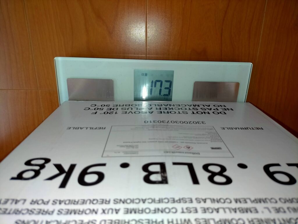 パナソニック体重計EW-FA13でエアコン冷媒ガスR32(充填済みシリンダー)を測定した結果17.3kg表示。分解能100gのため大まかな表示のみ。SF-890との比較でSF-890が17.236kgを表示し100g単位より精密な充填量管理が可能なことを実証