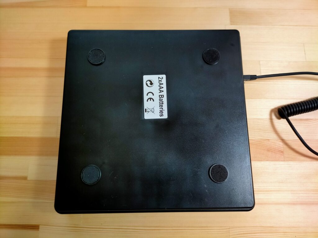 SF-890デジタル台はかりの計量皿(250×250mm)裏面。グリップ性の高いゴム足が4カ所付きでずれにくい構造。ただし無垢材テーブルや木製家具の上で使用するとゴムが黒い跡を残すため対策が必要