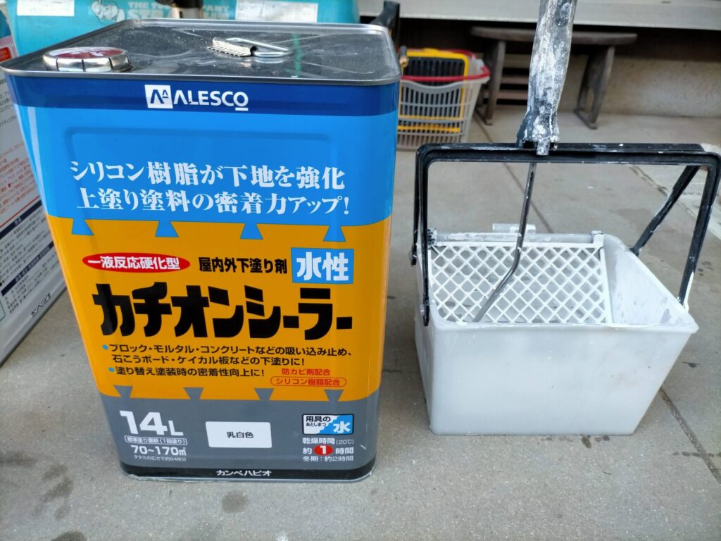 軒天用ケイカル板（6×3尺・厚み6mm）にカンペハピオ水性カチオンシーラー乳白色をローラーで下塗りしている工程。取り付け前に6×3尺のまま平地で塗装することで高所での塗装作業を減らす効率的な工程順。しっかり攪拌して薄めず使用