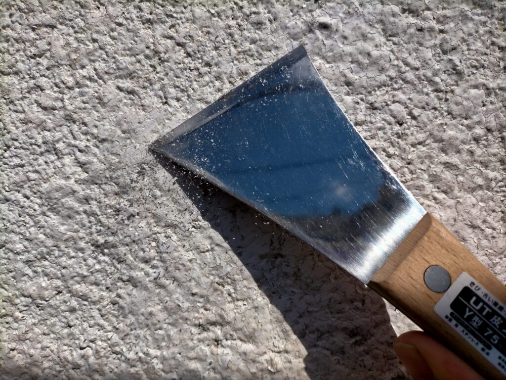 モルタル外壁塗装の下地調整作業。高儀TAKAGI貫通皮スキY型75mm・ワイヤーブラシ・スコッチブライトで剥がれかけた古い塗膜を除去している状態。皮スキはスクレーパーより強く古い塗膜除去・隙間への押し込み・ベニヤ板抜き出しなど用途が幅広く使い勝手が良い