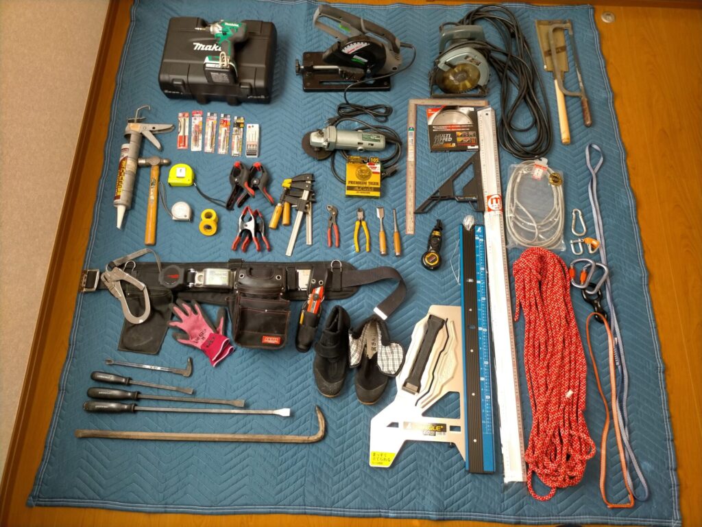 軒天修理DIYに使用した工具一覧の実物写真。高儀EARTH MAN丸ノコCS-100TA（165mm）・差し金・スケール・定規・インパクトドライバー・釘抜・プライヤー・多機能はしご・白幡瓦資材止G-6・いらかくんHL-36・藤井電工安全帯・登山用ロープ30m・スリング120cm/60cm・カラビナ・腰袋