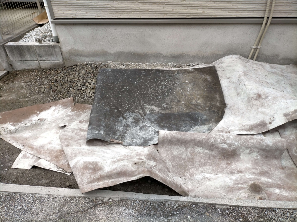 犬走りの石灰砕石を取り除いた後にデュポン ザバーン240防草シート（厚さ0.64mm）を剥がしている作業の様子。2019年4月施工から2年半後も繊維にコシが残り良好な状態