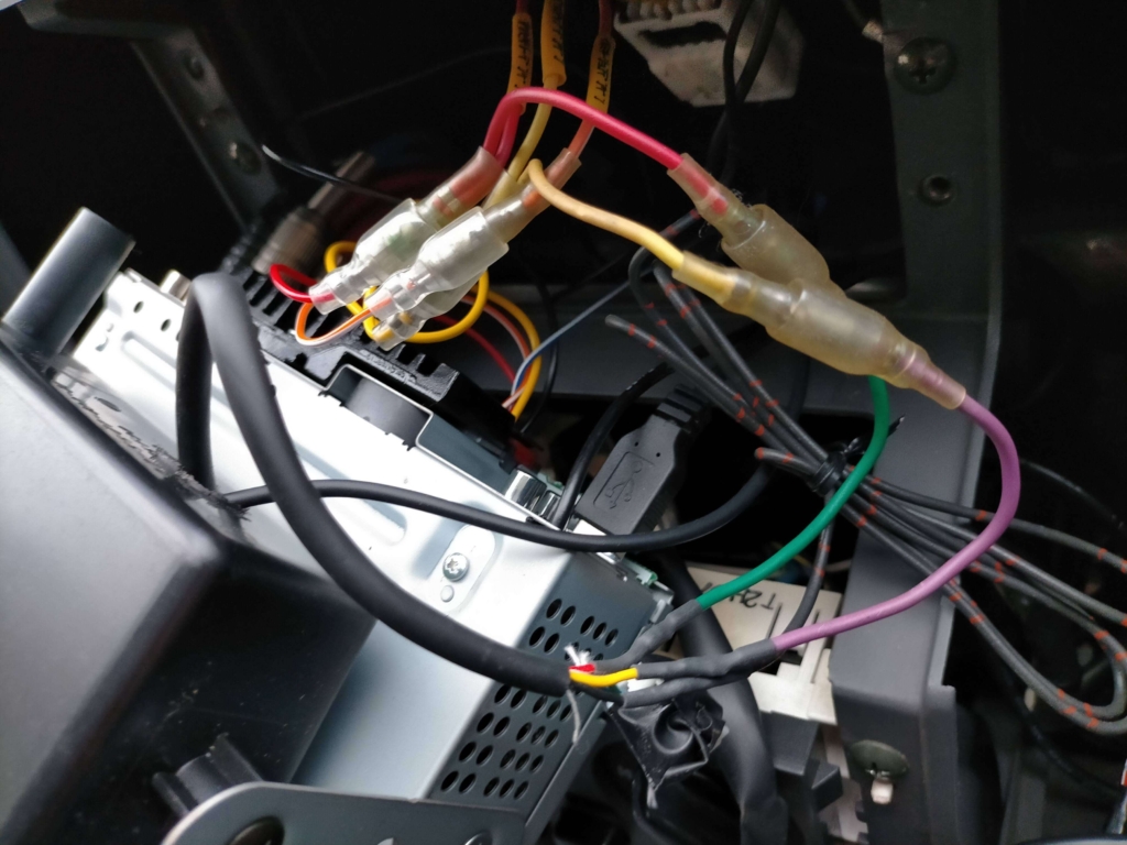 E25キャラバン/いすゞコモの1DINポケット加工穴にETC2.0車載器DIU-C010の電源線・アンテナ線を通してポケット内に本体を収めた状態。取り出しやすいようマジックテープで仮固定する前の配線通し完了段階