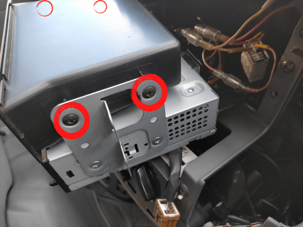 E25キャラバン/いすゞコモのオーディオブラケットから1DINポケット（小物入れ）を取り外す固定ネジ4本の位置を示した図解。オーディオを引き出した後にブラケットから1DINポケット単体を取り外すための手順説明