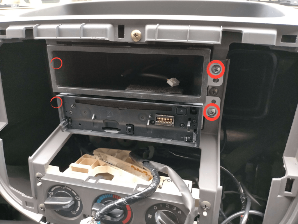 E25キャラバン/いすゞコモのオーディオブラケット（BKT）固定ネジ4本の位置を赤丸で示した図解。センタークラスター取り外し後にアクセス可能なネジ位置の案内。このネジを外すとオーディオと1DINポケットを手前に引き出せるE25キャラバン/いすゞコモのオーディオブラケット（BKT）固定ネジ4本の位置を赤丸で示した図解。センタークラスター取り外し後にアクセス可能なネジ位置の案内。このネジを外すとオーディオと1DINポケットを手前に引き出せる