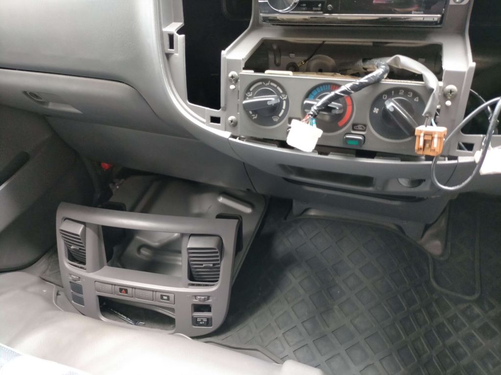 E25キャラバン/いすゞコモのセンタークラスター取り外し手順③・引き出したパネルのハザードスイッチ等の配線コネクターを切り離してセンタークラスターを完全撤去した状態。この後オーディオブラケット固定ネジ4本にアクセスできる