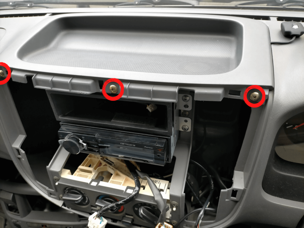 E25キャラバン/いすゞコモのダッシュボードセンタートレイ（ネジ3本＋爪）の固定ネジ位置を示した図解。ETCアンテナケーブルをダッシュボード内に配線するためのトレイ取り外し手順案内