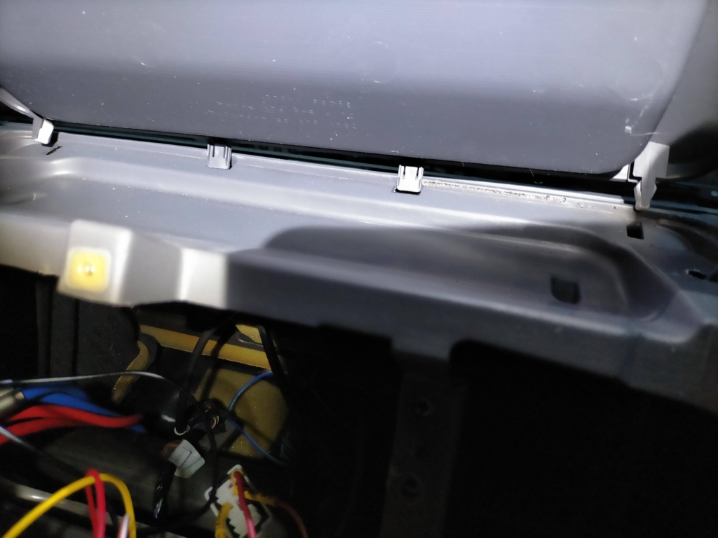 E25キャラバン/いすゞコモのダッシュボードセンタートレイ奥側の爪4本の位置確認。手前ネジ3本を外した後に奥側の爪4本を真上に引き抜くと外れる正しい取り外し方法。内張りはがしを使うとツメを折らずに取り外せる