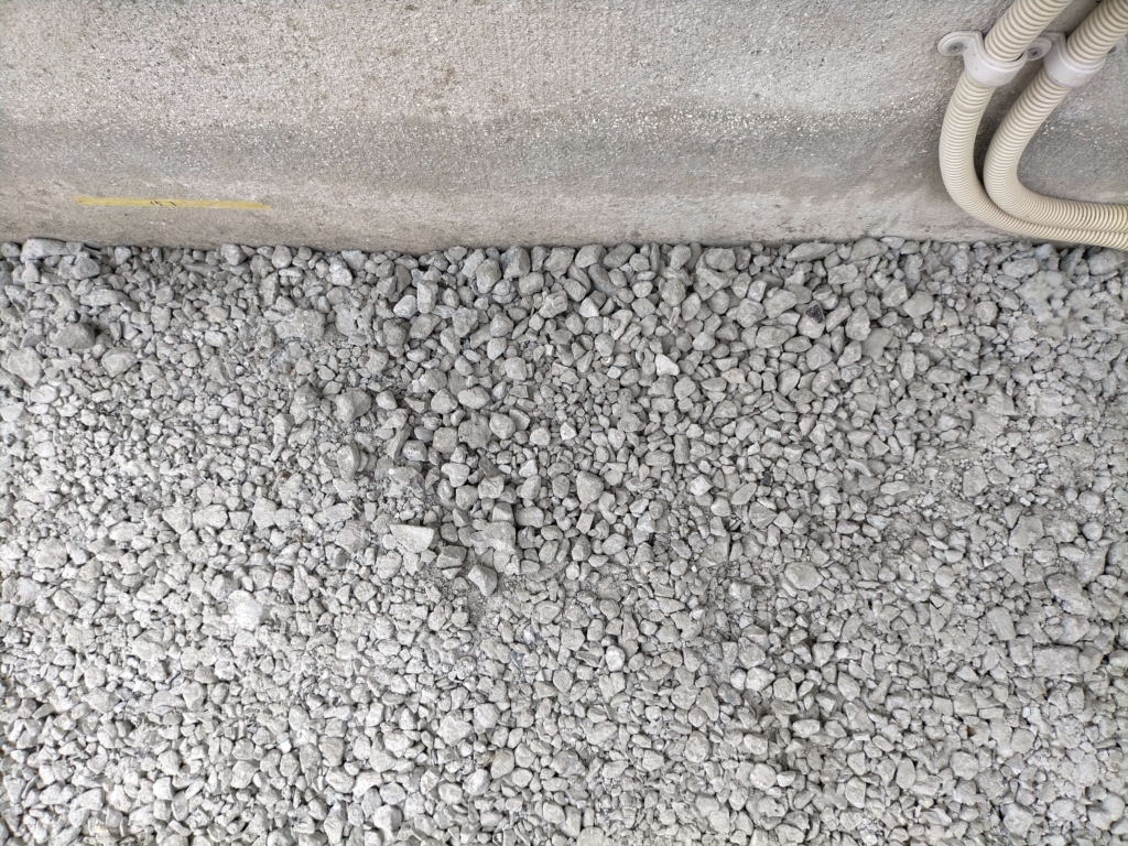 ポーラスコンクリート打設翌日に発生した表面が固まっていない箇所のクローズアップ。転圧のやりすぎ（固まりかけに2時間おき3〜4回転圧）と終盤の水分不足による配合ムラが原因の失敗例