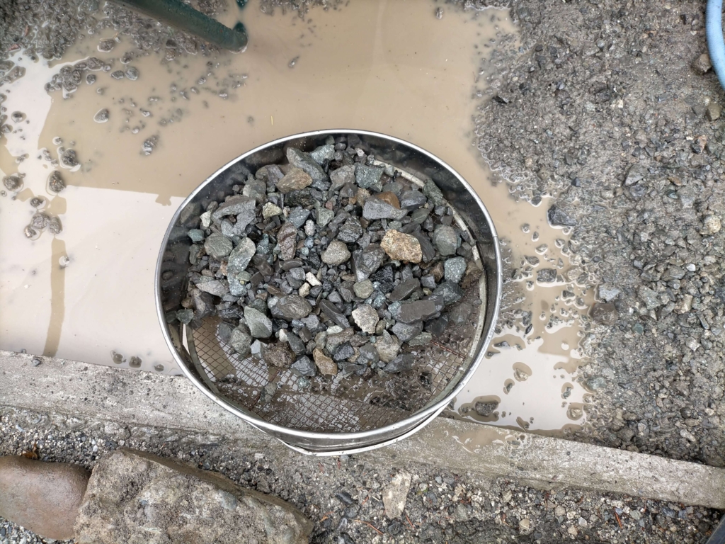 掘削した残土を手作業でふるいにかけて砕石（粗骨材）を取り出している様子。ポーラスコンクリートDIYのコスト削減策として、購入不要の現地採取砕石を約490kg（0.3㎥分）確保。最も労力を要した作業