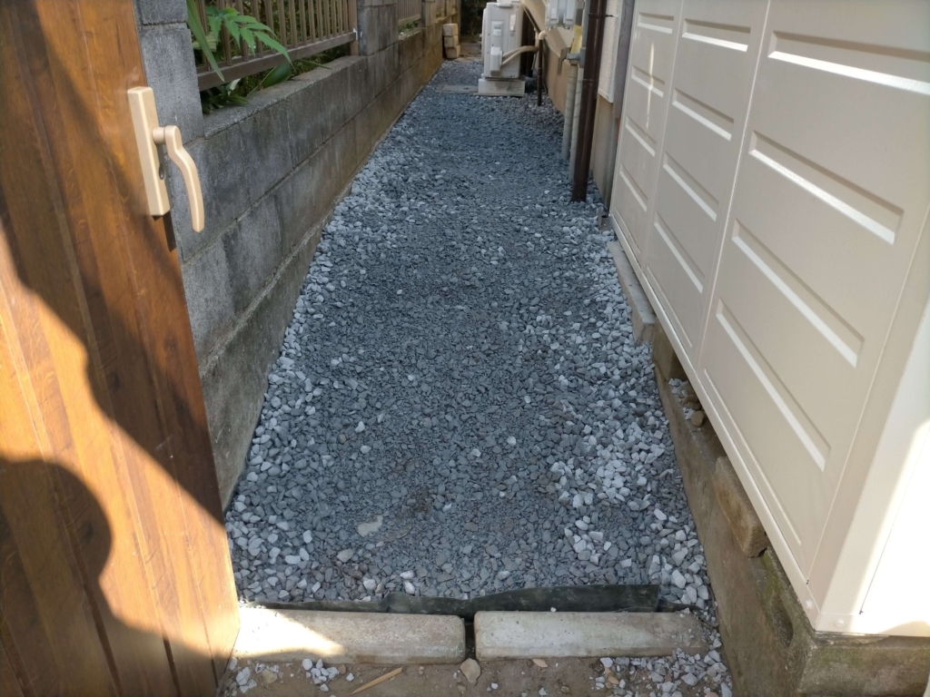 ザバーン240防草シートの上に石灰砕石800kgを男性3人がスコップで8〜9cm厚に敷き終えた犬走りの完成状態。乾燥後は白系の美しい仕上がりになる。施工サイズ約8.8㎡